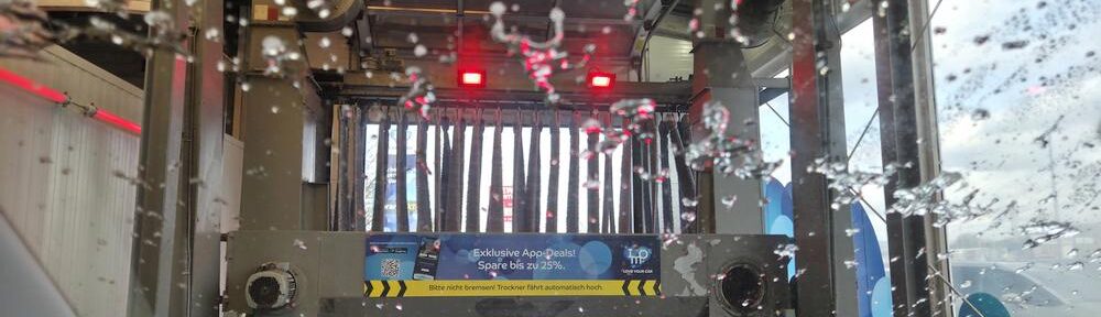 Blick aus dem Auto auf rotierende Bürsten in der Waschanlage.