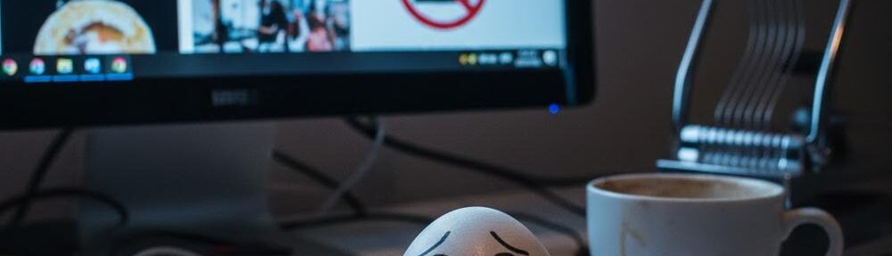 Ein sichtlich traumatisiertes Moralei sitzt auf einem Notizblock am Schreibtisch. Im Hintergrund leuchtet ein Monitor mit dem Blog-Beitrag „Das Grauen in der Küche“, während ein Eierschneider bedrohlich daneben aufragt.