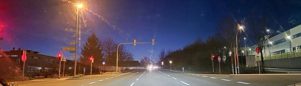 Früher Morgenhimmel mit hellem Streifen über dunkler Straße.