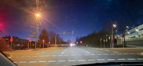 Früher Morgenhimmel mit hellem Streifen über dunkler Straße.