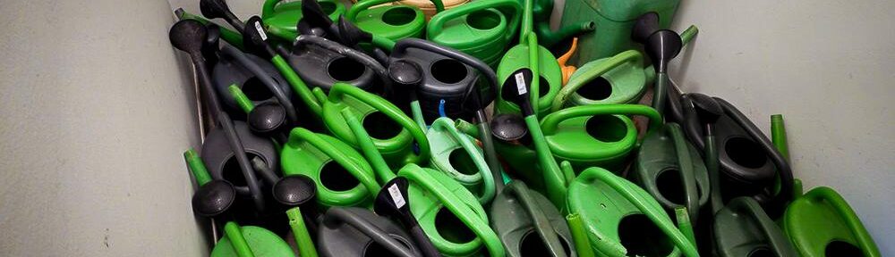 Gießkannen drängen sich in einem Lager dicht in eine Ecke.