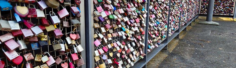 Hunderte Liebesschlösser an einer Fußgängerbrücke, bunt, verrostet und voller unbekannter Geschichten.