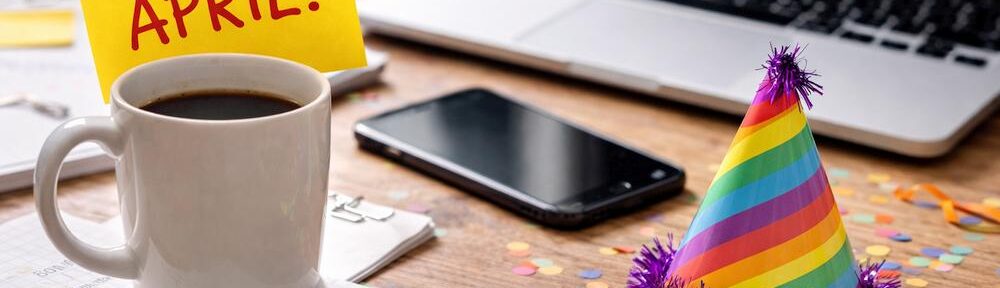 KI-generiertes Bild eines zwangslustigen Schreibtischs mit Kaffee, Laptop und April-Kram als Symbol für den 1. April.