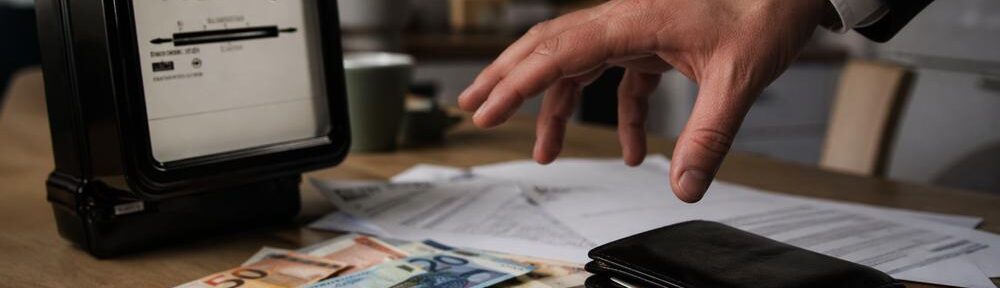 Stromzähler, Geld und zugreifende Hand als Bild für das Abkassieren beim Strom. KI-generiertes Bild