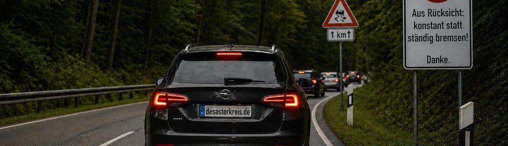 Zäher Kolonnenverkehr auf nasser Landstraße, ein unruhiger Vordermann zerlegt den Fahrfluss, Bild KI-generiert.