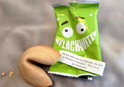 Geöffneter Flachwitz-Keks mit grüner Verpackung und einem Witz über Elefanten, die sich in Bäumen verstecken.