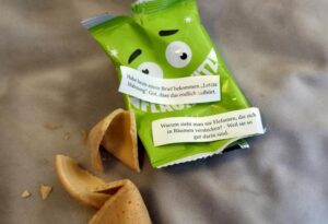 Angefressener Flachwitz-Keks mit grüner Verpackung und zwei Sprüchen über letzte Mahnungen und versteckte Elefanten.