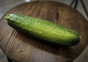 Grüne Zucchini aus eigenem Anbau auf einem runden Holztisch