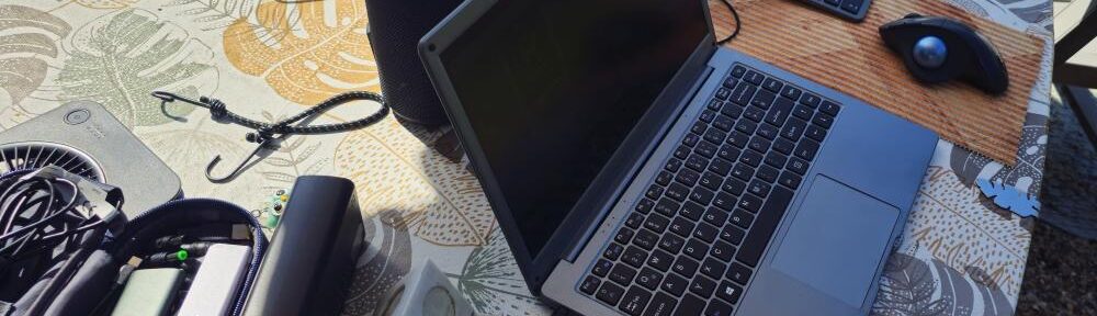 Mobiler Arbeitsplatz im Garten mit Notebook, Powerbanks, Bluetoothlautsprecher und Solarpaneel.