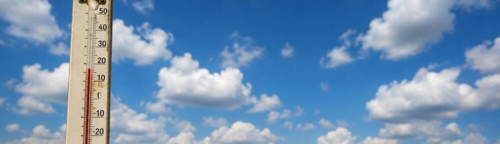 Blauer Wolkenhimmel mit Thermometer und verbogenem Zollstock als Sinnbild für Wetter, Messung und verschobene Maßstäbe.