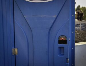 Blaue mobile Toilette auf einer Baustelle bei sommerlichem Wetter.